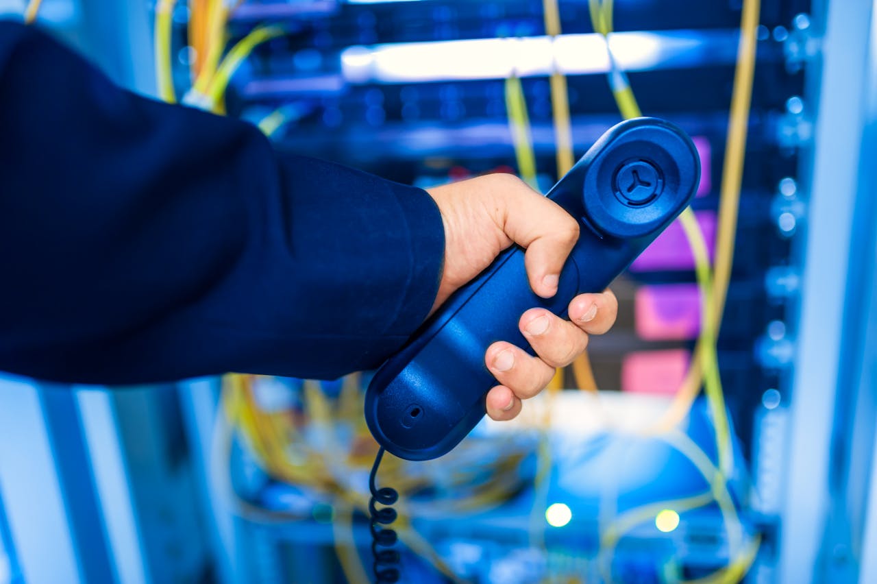 man holding phone in front of computer network cables